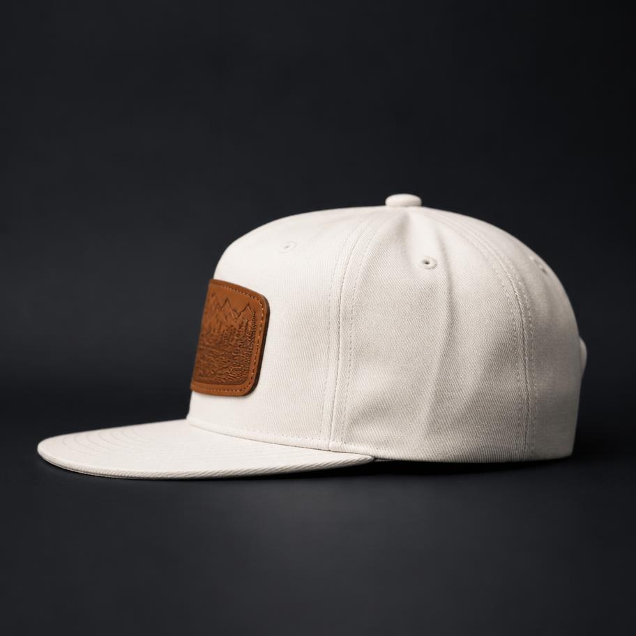 Off-white canvas cap with a saddle tan engraved leather patch